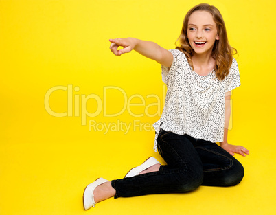 Smiling young girl pointing away