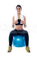 Attractive female athlete sitting on blue ball