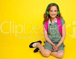 Pretty girl kid listening to music. Seated on floor