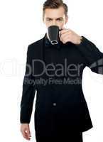 Smart young man drinking coffee in black cup