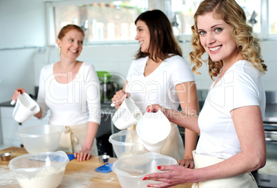 Female bakers pouring water into a plastic bowl