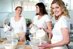 Female bakers pouring water into a plastic bowl