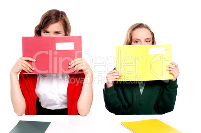 Naughty schoolgirls hiding behind the book