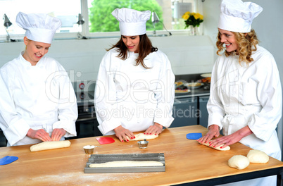 Beautiful female chefs kneading dough