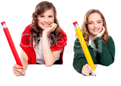 Beautiful schoolgirls posing with big pencil