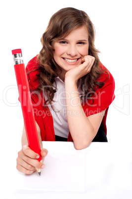 Happy teenager writing with big red pencil