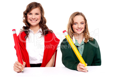 Female students writing with big pencil