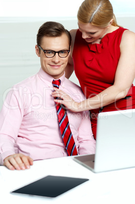 Female adjusting her co-workers tie