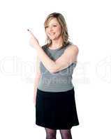Smiling woman pointing towards copy space area