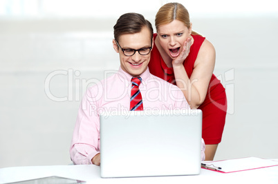 Shocked woman looking into laptop. Man working