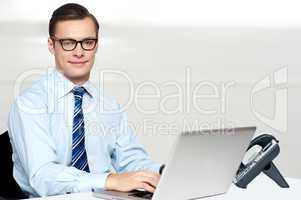 Handsome corporate male tying on laptop