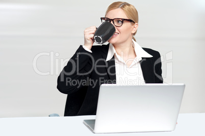 Businesswoman enjoying coffee at work desk