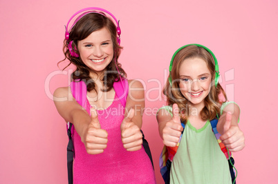 Two beautiful schoolgirls giving thumbs up