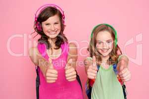 Two beautiful schoolgirls giving thumbs up