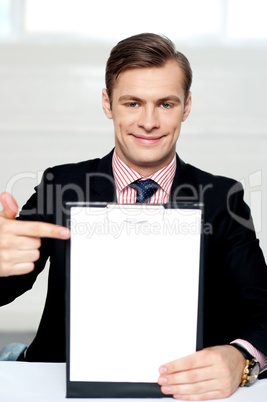Smiling man pointing towards blank clipboard