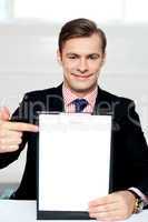 Smiling man pointing towards blank clipboard
