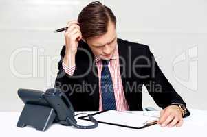 Confused young man itching his head with pen