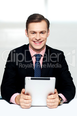 Cheerful male executive holding digital device