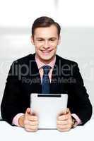 Cheerful male executive holding digital device