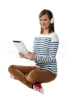 Seated girl enjoying music on portable device