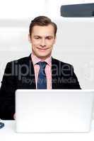 Attractive smiling man operating a laptop