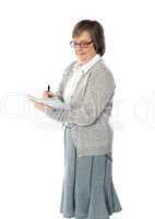 Senior woman writing in spiral notebook