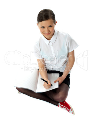 Aerial view of charming schoolgirl doing homework