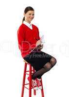 Girl sitting on high stool writing in notebook
