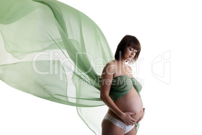 Pretty pregnant woman with green blowing fabric