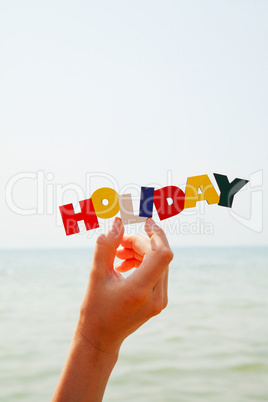 Female's hand holding colorful word 'Holiday'