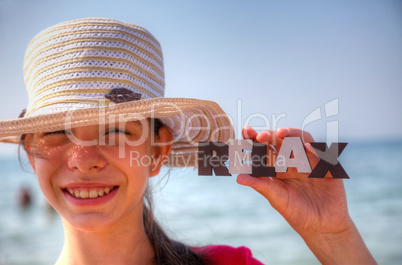 Teen girl at a beach holding word 'Relax'