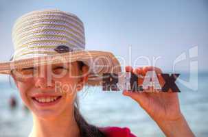 Teen girl at a beach holding word 'Relax'