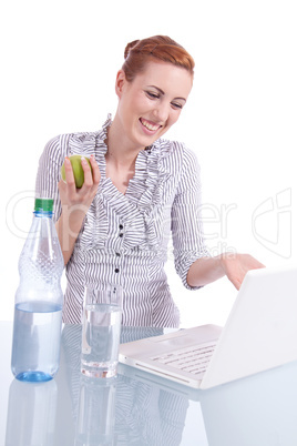 Junge Frau mit Laptop und Snack am Schreibtisch