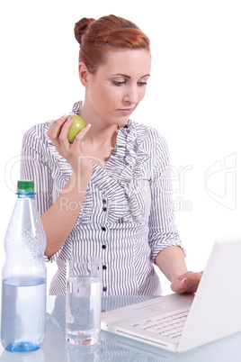 Junge Frau mit Laptop und Snack am Schreibtisch