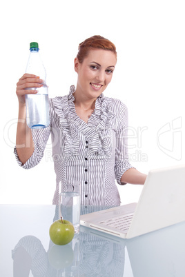 Junge Frau mit Laptop und Snack am Schreibtisch