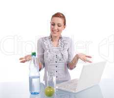 Junge Frau mit Laptop und Snack am Schreibtisch
