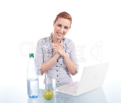 Junge Frau mit Laptop und Snack am Schreibtisch