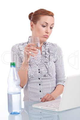 Junge Frau mit Laptop und Snack am Schreibtisch