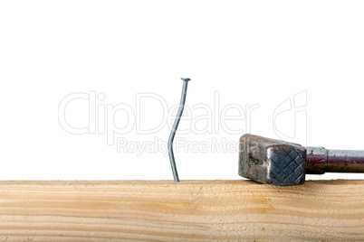 Crooked nail in the wooden board with a hammer