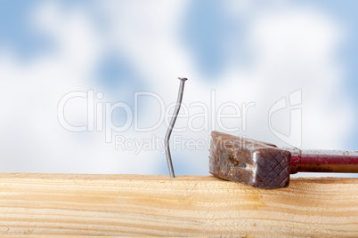 Crooked nail in the wooden board with a hammer