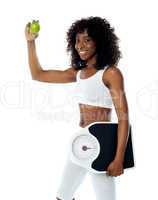 Athlete holding green apple and weighing machine