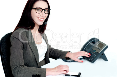 Attractive female executive dialing clients number