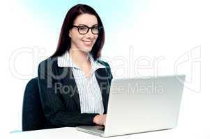 Cheerful corporate woman using laptop