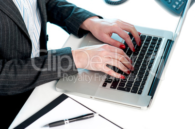 Females hands typing on laptop keypad. Cropped image
