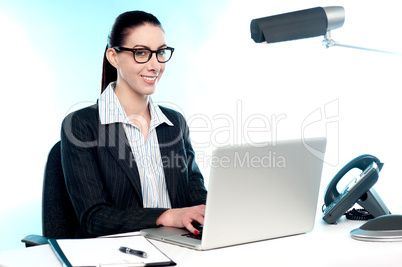 Smiling female secretary working on laptop