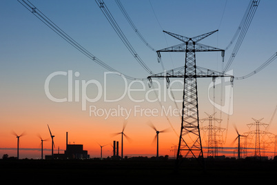 Strommasten bei Sonnenuntergang mit Windrädern und Kernkraftwerk
