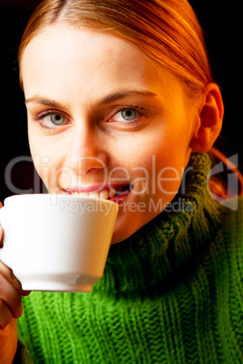 beautiful young woman drinking cappuccino and looking at camera