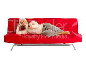 elderly woman on the sofa with television remote control