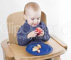 young child eating peaches in high chair