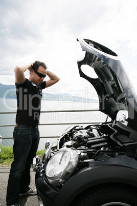 sad man looking at his broken car